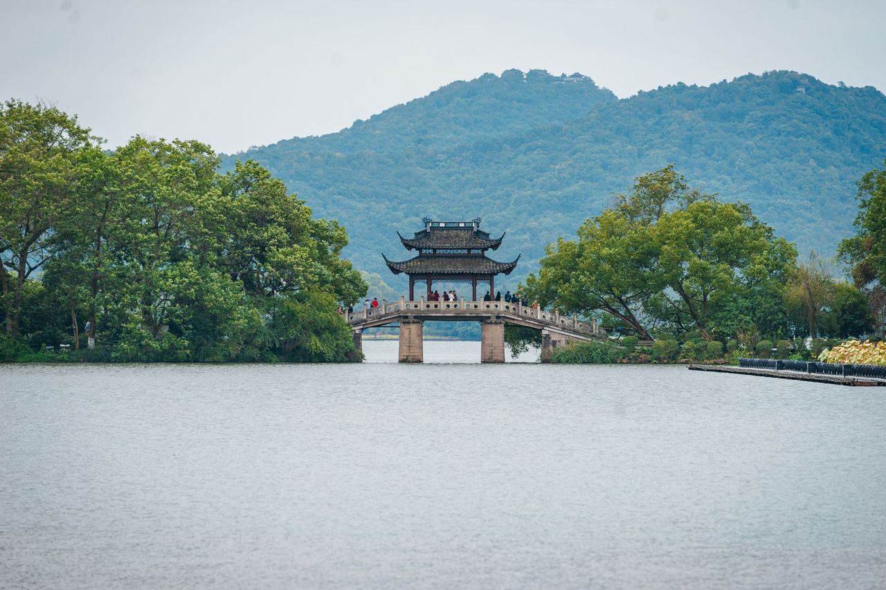 The arched Broken Bridge with its pavilion, against the wooded ridge north of the lake
