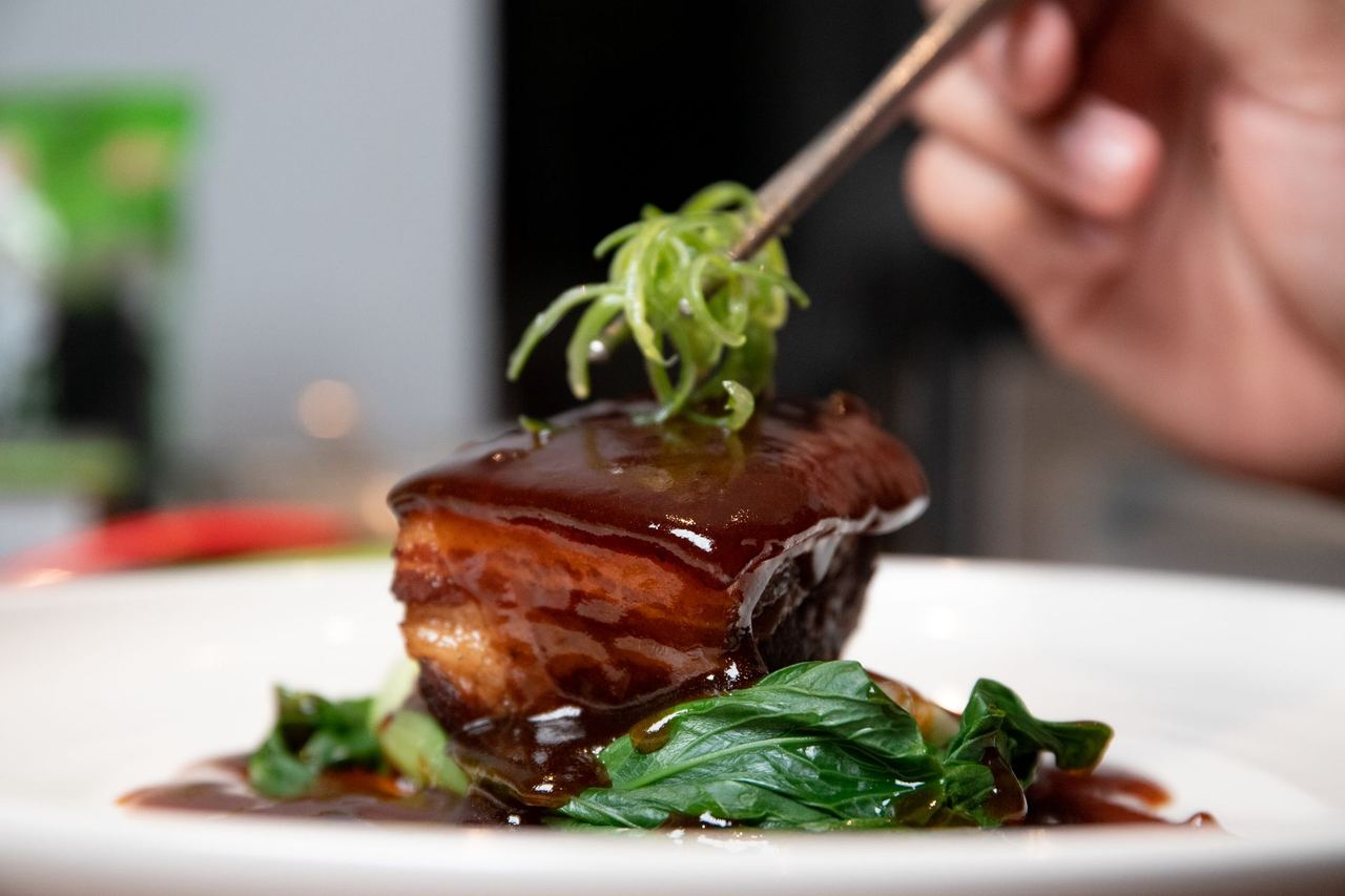 A glazed cube of Dongpo pork, slow-braised pork belly, with greens
