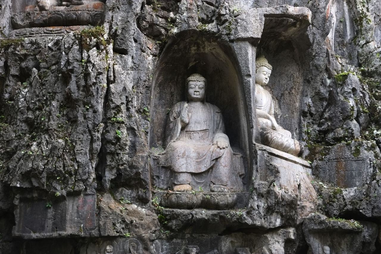 Buddhist figures carved into arched niches in the rock face at Feilai Feng