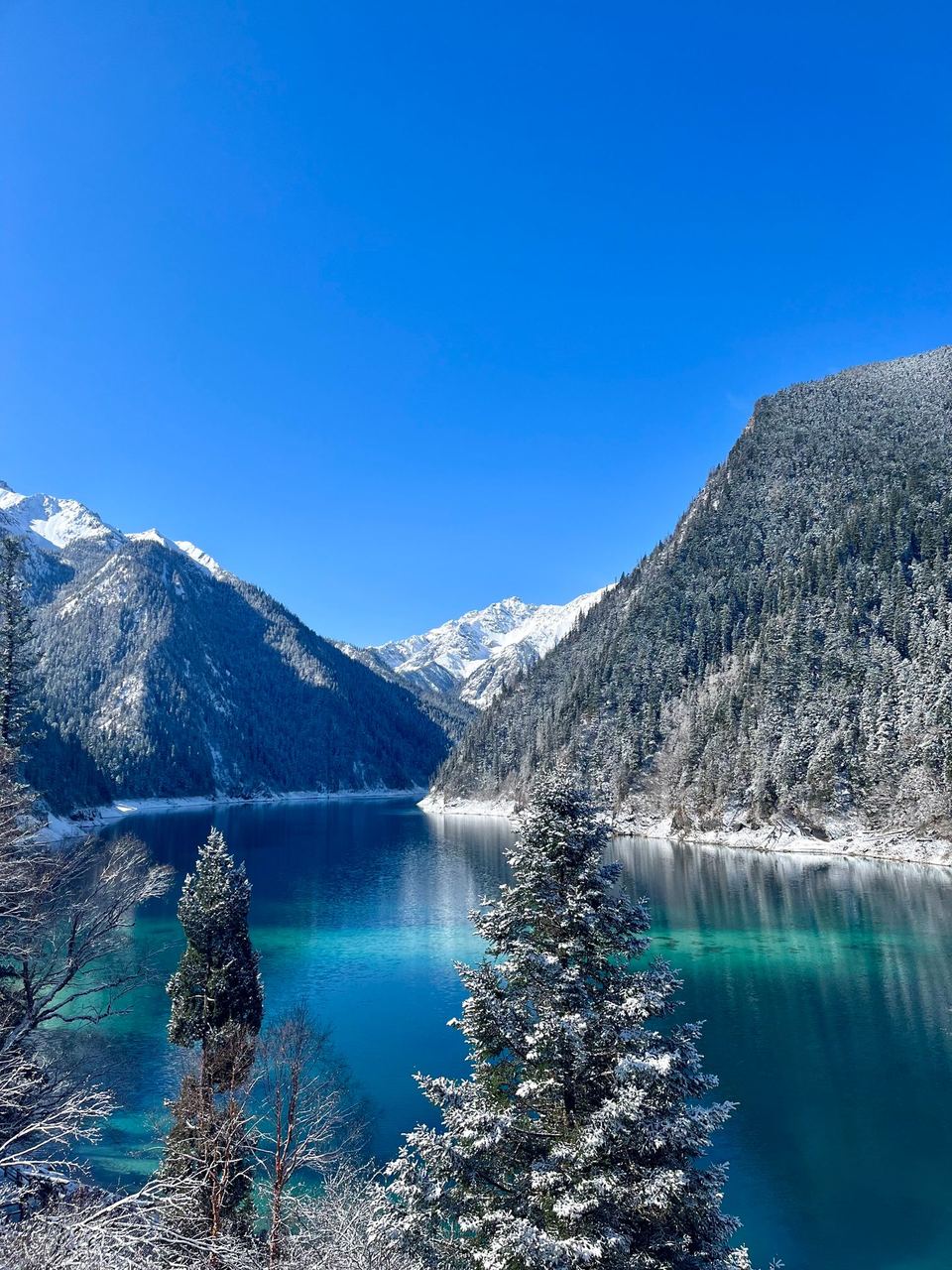 A Jiuzhaigou lake in winter, mountains white and the water still impossibly blue