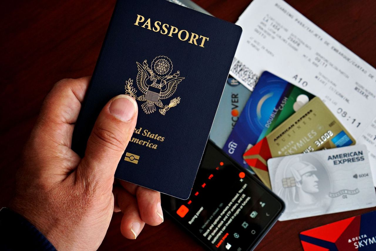 A US passport with travel documents, cards and a phone laid out before a trip